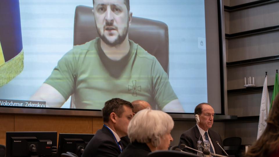 Ukrainian President Volodymyr Zelenskyy is seen speaking on a screen above World Bank Group President David Malpass at the World Bank Group 2022 Spring Meetings Ministerial Roundtable for Support to Ukraine on 21 April 2022. Photo: Paul Blake / WorldBank 